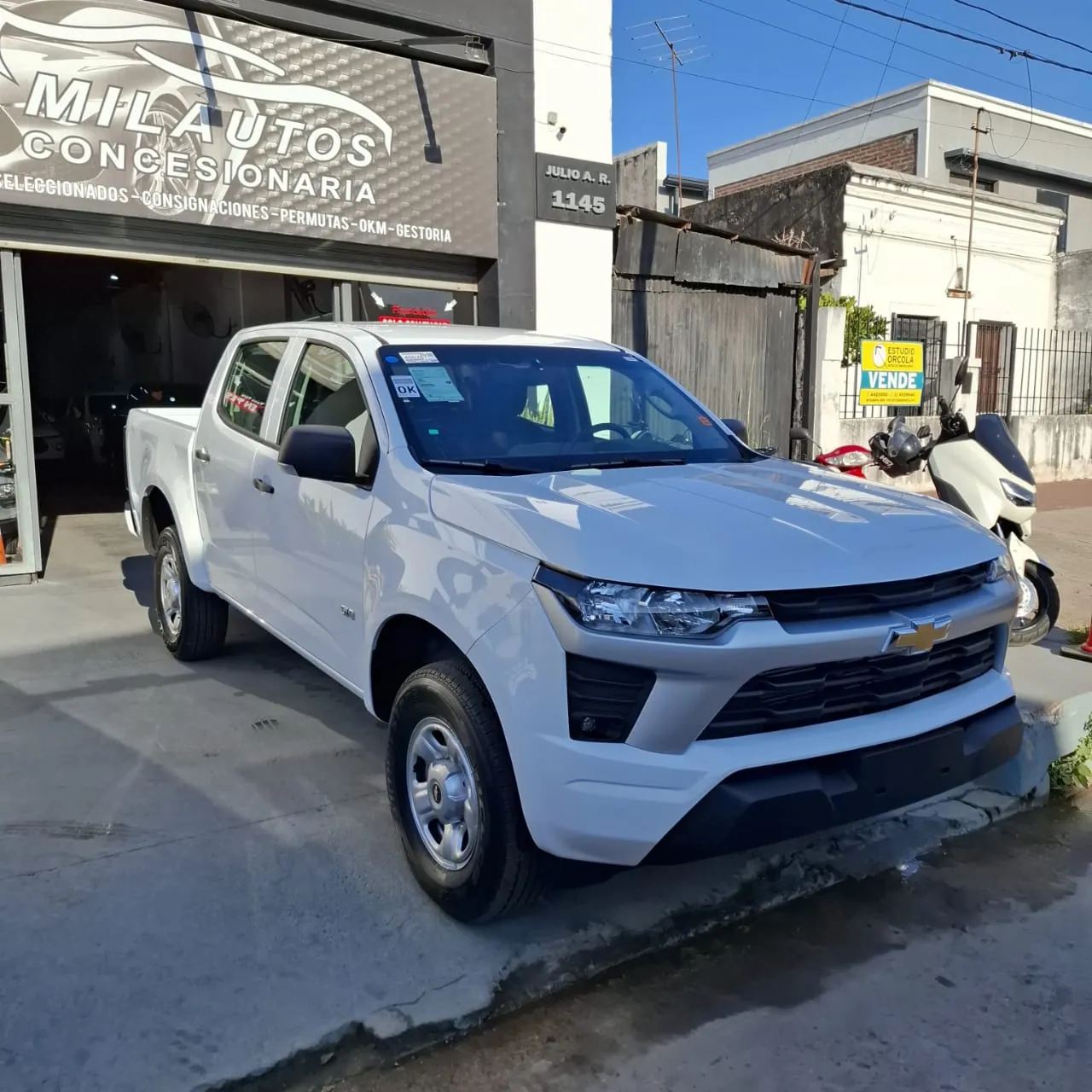 Frente de Mil Autos en Julio A. Roca 1145, con el cartel y una Chevrolet S10 en la vereda